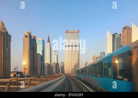 Système de métro. Vue depuis la fenêtre du wagon de métro à Dubaï sous les rayons du coucher du soleil. Le train de la station de métro souterrain passe devant des gratte-ciel Banque D'Images