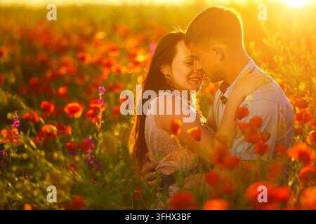 L'homme et de la femme en champ de coquelicots au coucher du soleil, romance Banque D'Images