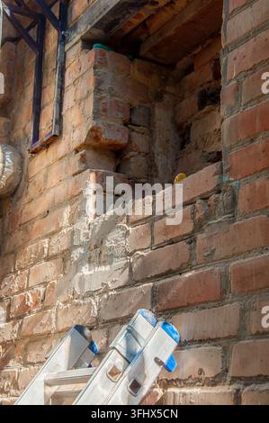 Chantier avec échelle et ouverture de mur en briques inachevée Banque D'Images