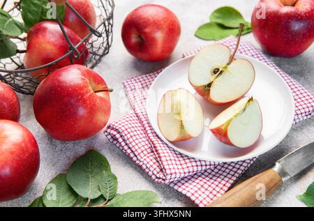 Des pommes rouges fraîches dans un panier et coupées en tranches dans une assiette Banque D'Images