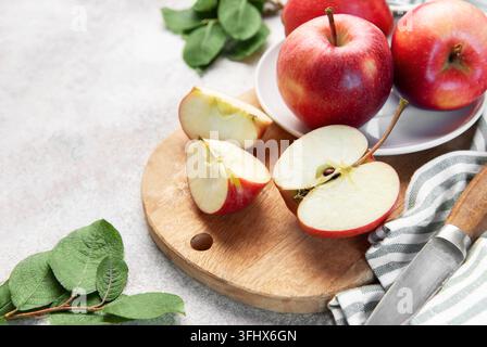 Des pommes rouges fraîches tranchées sur une planche en bois Banque D'Images