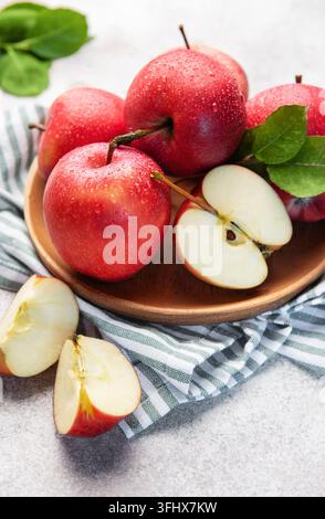Des pommes rouges saines avec des gouttes d'eau sur une assiette en bois Banque D'Images