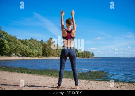 Vue de dos d'une belle jeune femme mince en doudoune et leggings, faisant du sport Banque D'Images