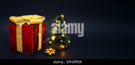 Coffret cadeau avec petit sapin de Noël sur fond noir Banque D'Images