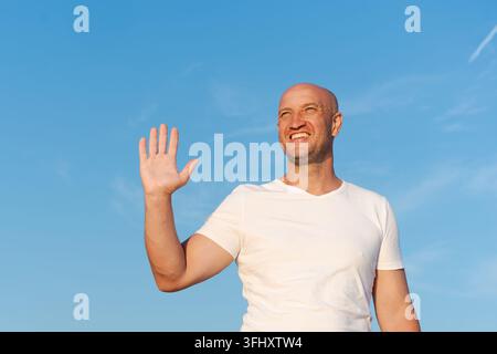 Homme chauve souriant et faisant un signe de la main Banque D'Images