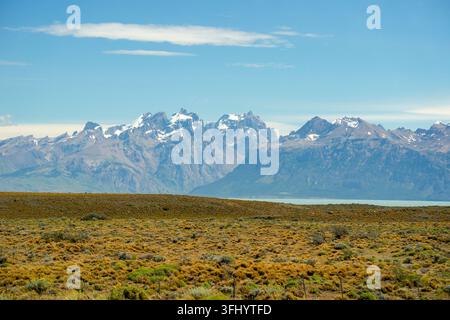 Vaste paysage de steppe dorée près d'El Calafate avec des sommets dramatiques des Andes enneigés et un lac glaciaire en Patagonie, Argentine. Banque D'Images