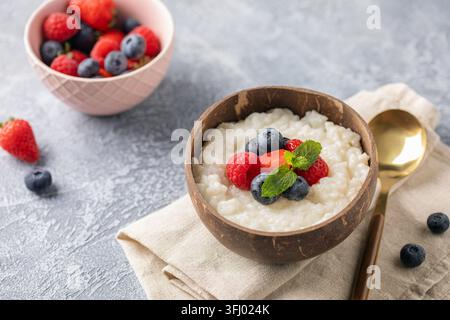 Bouillie de lait de riz avec des baies dans un bol sur la table. Petit déjeuner sain Banque D'Images