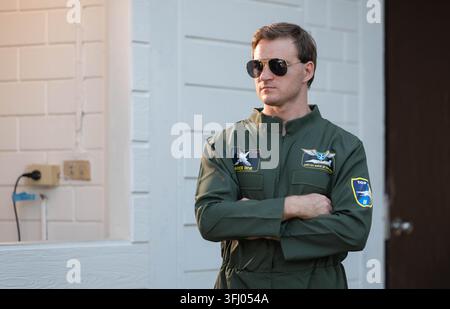 Pilote masculin confiant en combinaison de vol verte portant des lunettes d'aviateur, debout les bras croisés en plein air Banque D'Images