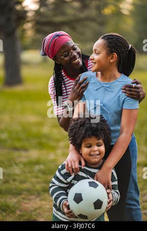 Mère et enfants jouant au football dans le parc Banque D'Images