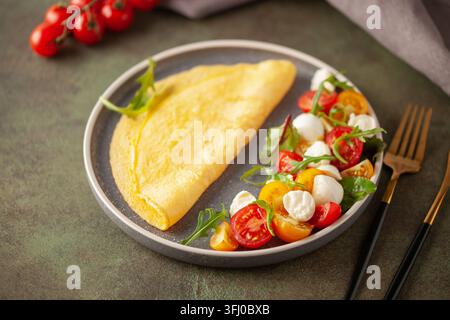 Salade avec roquette, mozzarella et tomates dans une assiette sur la table. Omelette avec salade Caprese. Banque D'Images