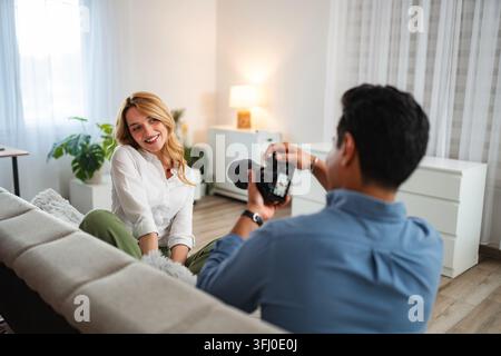 Photographe capturant le portrait d'une femme heureuse lors d'une séance photo en intérieur Banque D'Images
