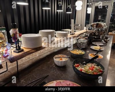 Disposition élégante de buffet de petit-déjeuner mettant en vedette des piles d'assiettes blanches, des plats salés et des légumes colorés disposés sur une surface en marbre poli à l'intérieur Banque D'Images
