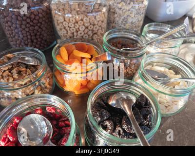 Conteneurs en verre remplis de noix, d'abricots secs, de raisins secs, de prunes et de copeaux d'amandes, disposés pour un petit-déjeuner organisé du matin Banque D'Images