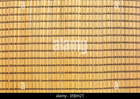 Texture de natte à sushi asiatique tissée en bandes de bambou avec points de fil noir dans un ton beige doré Banque D'Images