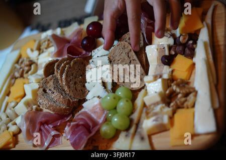 une planche d'apéritif ou de hors-d'œuvre avec une sélection de fromages variés, de viandes séchées, de tranches de pain rustique, de raisins, de noix et de raisins secs Banque D'Images