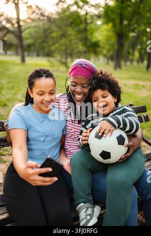 Mère et enfants qui créent un lien en prenant un selfie dans le parc Banque D'Images