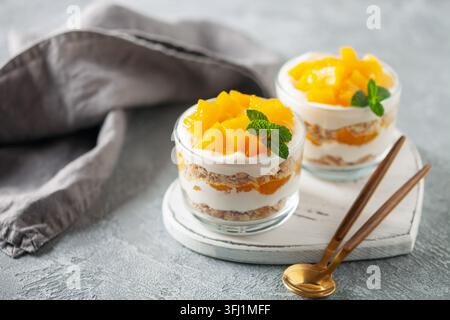 Délicieux gâteau flotté à la mangue dans des verres sur planche de bois. Cuisine sucrée philippine Banque D'Images