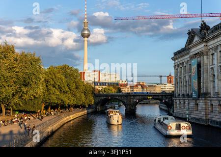 Berlin, Allemagne. 15 SEP 2026. La tour de télévision s’élève au-dessus de la Spree alors qu’un tramway traverse un pont et que des foules se rassemblent le long du front de mer, montrant les transports urbains Banque D'Images