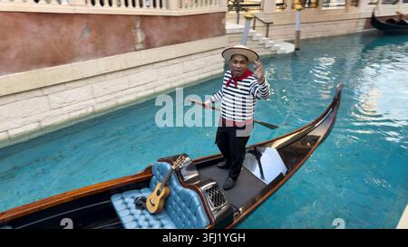Gondolier accueillant les visiteurs depuis une gondole sur le canal intérieur du Venetian Macao à Macau, en Chine Banque D'Images