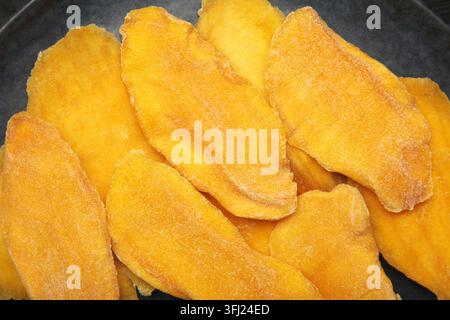 Tranches de mangue séchée sur fond noir. Vue de dessus Banque D'Images