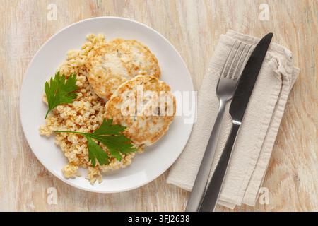Escalopes de poulet ou de légumes avec un plat d'accompagnement de boulgour dans une assiette sur la table. Nutrition diététique. Vue de dessus Banque D'Images