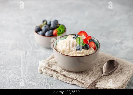 Bouillie d'avoine aux bleuets et fraises à la menthe fraîche dans un bol en céramique. Petit déjeuner sain Banque D'Images