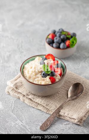 Bouillie d'avoine aux bleuets et fraises à la menthe fraîche dans un bol en céramique. Petit déjeuner sain Banque D'Images
