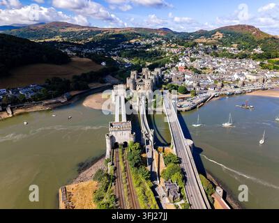 Prise de vue par drone de la forteresse médiévale de Conwy et du pont suspendu de Thomas Telford, montrant les tours en pierre et la voie ferrée menant aux murs du château. Banque D'Images