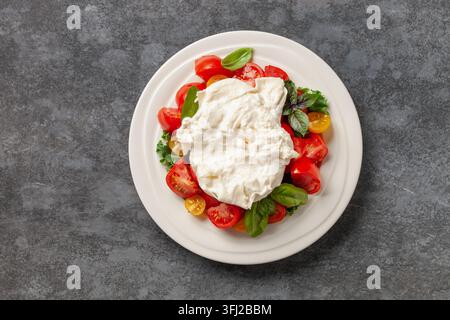 Fromage de salade italien burrata ou stracciatella avec des tomates sur une assiette. Vue de dessus Banque D'Images