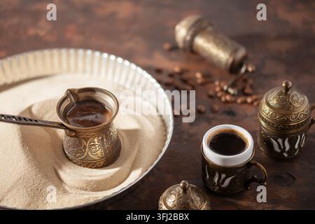 Café turc traditionnel au cezve préparé sur du sable chaud. Banque D'Images