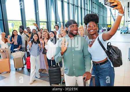 Groupe divers d'amis prenant un selfie à l'aéroport Banque D'Images