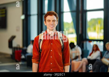 Jeune homme souriant et debout dans le terminal de l'aéroport Banque D'Images