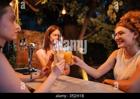 Amies dégustant des cocktails au bar d'été en profitant de la vie nocturne Banque D'Images