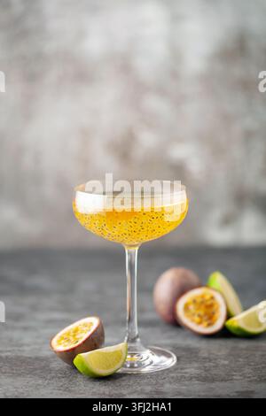 Cocktail martini fruit de la passion. Boisson alcoolisée aigre avec fruits de la passion frais et citron vert, avec des outils de bar. Banque D'Images