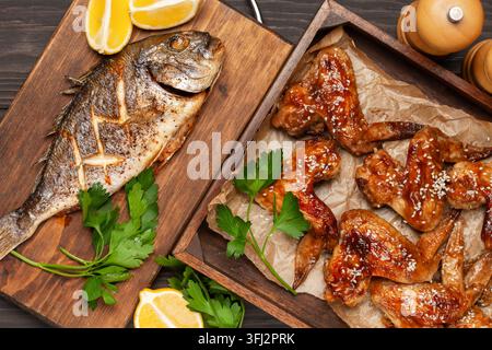 Ailes de poulet griller dans la sauce teriyaki avec sésame dans un plateau en bois poisson dorado sur un fond en bois. Vue de dessus Banque D'Images