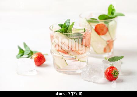 Boissons glacées rafraîchissantes d'été avec concombre, fraise et menthe sur fond blanc. Eau infusée Banque D'Images