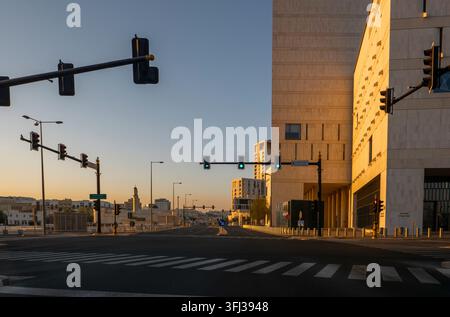 Intersection urbaine moderne avec feux de circulation et architecture contemporaine illuminée par la lumière dorée du matin à Msheireb Downtown, Doha. Banque D'Images