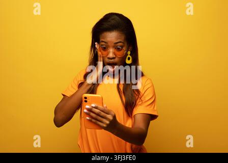 Concept lifestyle, technologie et personnes : Portrait d'une jeune Américaine inspirée, rêveuse et surprise utilisant son smartphone Banque D'Images
