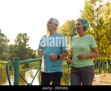 Couple de personnes âgées courant ensemble dans le parc en se regardant pendant les exercices de jogging et amincissement. Banque D'Images