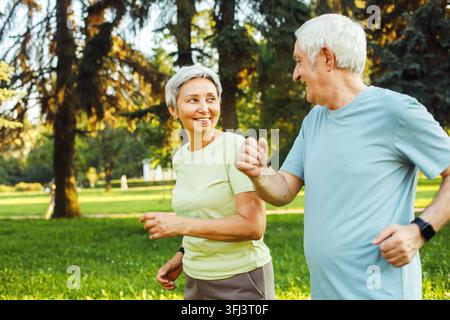 Couple de personnes âgées souriantes faisant du jogging dans le parc. Photo en gros plan. Banque D'Images