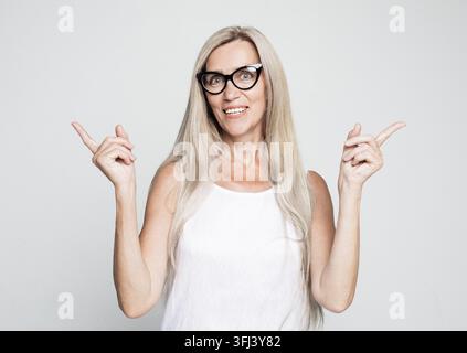 Femme âgée aux cheveux longs pointant avec les doigts et les bras levés. Banque D'Images