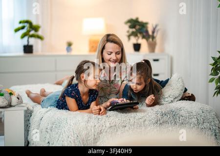 Mère et filles créant des liens tout en utilisant une tablette numérique Banque D'Images