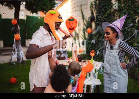Famille profitant d'une fête d'Halloween dans l'arrière-cour avec des enfants déguisés Banque D'Images