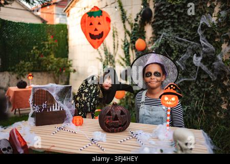 Enfants célébrant une fête d'Halloween dans des décorations de jardin Banque D'Images