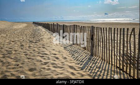 Barrière traditionnelle en bois ganivelle protégeant les dunes de sable sur une plage côtière de l'Atlantique à Soulac sur Mer, France. Banque D'Images