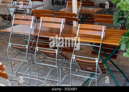 Des tables et chaises en bois vides sont disposées sur une terrasse extérieure tranquille. Banque D'Images