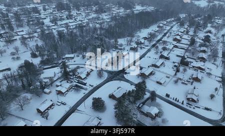 Quartier de banlieue tranquille d'une ville américaine après une chute de neige. Jour d'hiver froid et nuageux avec des toits enneigés de maisons unifamiliales. Carrefour dégagé un Banque D'Images
