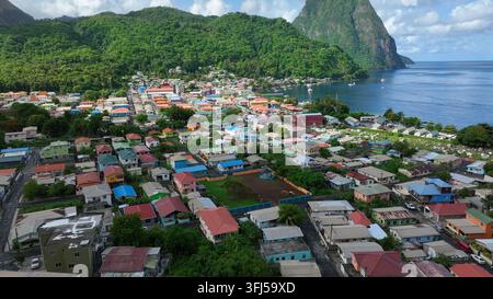 Vol de drone sur une ville colorée de l'île de Sainte-Lucie par une journée ensoleillée. Côte de montagnes vertes et toits colorés des maisons. Ville de Soufrière, Cari Banque D'Images
