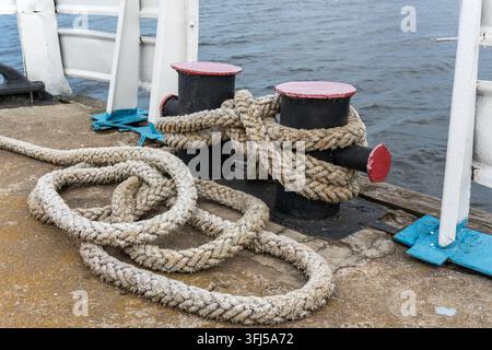 Boulon d'amarrage avec corde épaisse enroulée sur un quai en béton Banque D'Images