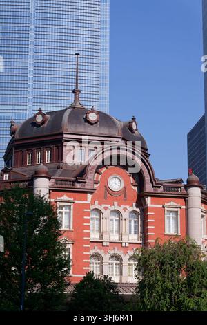 Un détail architectural en gros plan de l'icône du dôme en briques rouges de la gare de Tokyo juxtaposé à un gratte-ciel moderne en verre. Cette composition artistique e Banque D'Images
